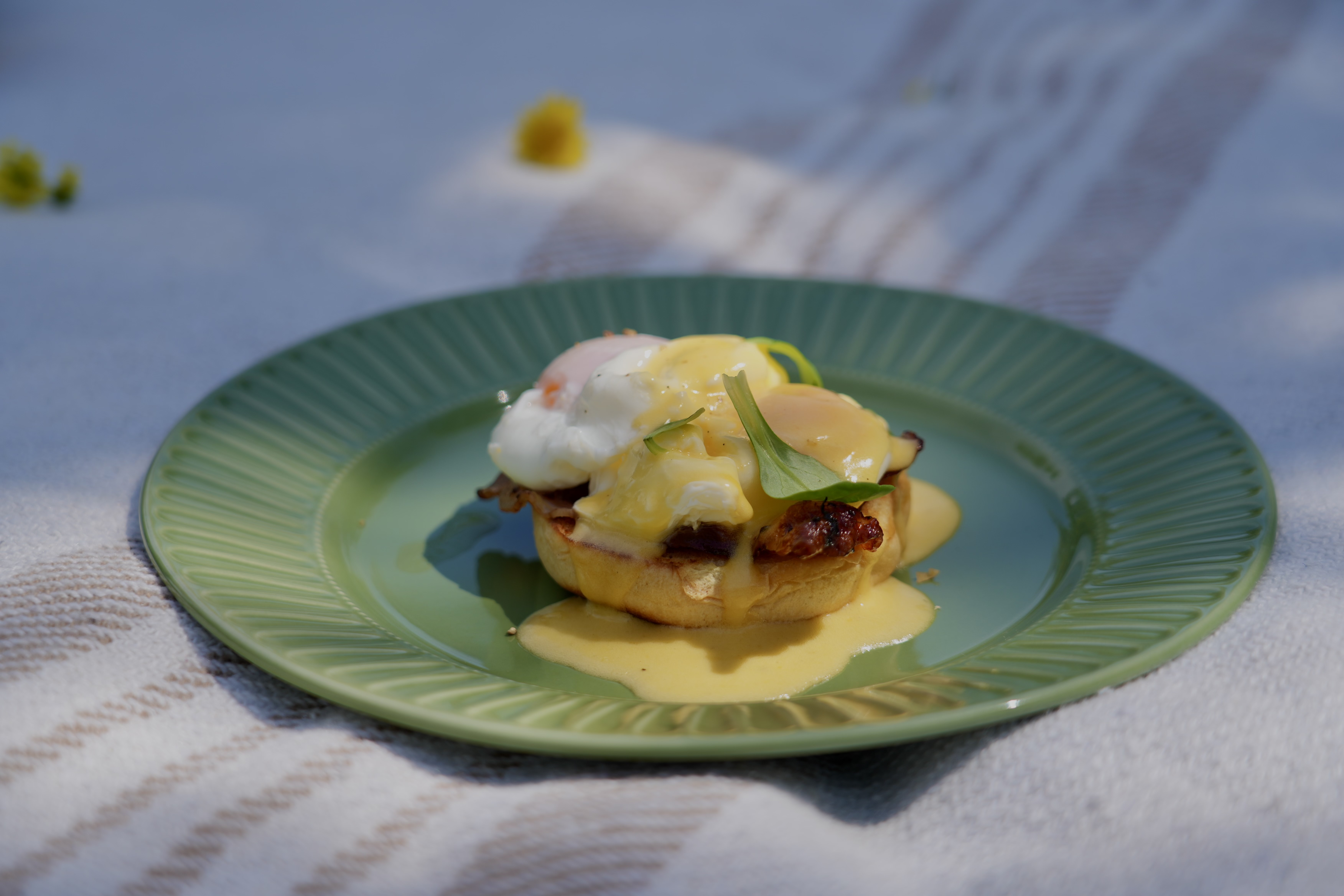 Close-up of Eggs Benedict with hollandaise sauce on a green plate — villa dining